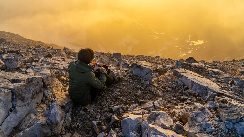 Girl on Vihren Peak during sunrise with very yellow sky